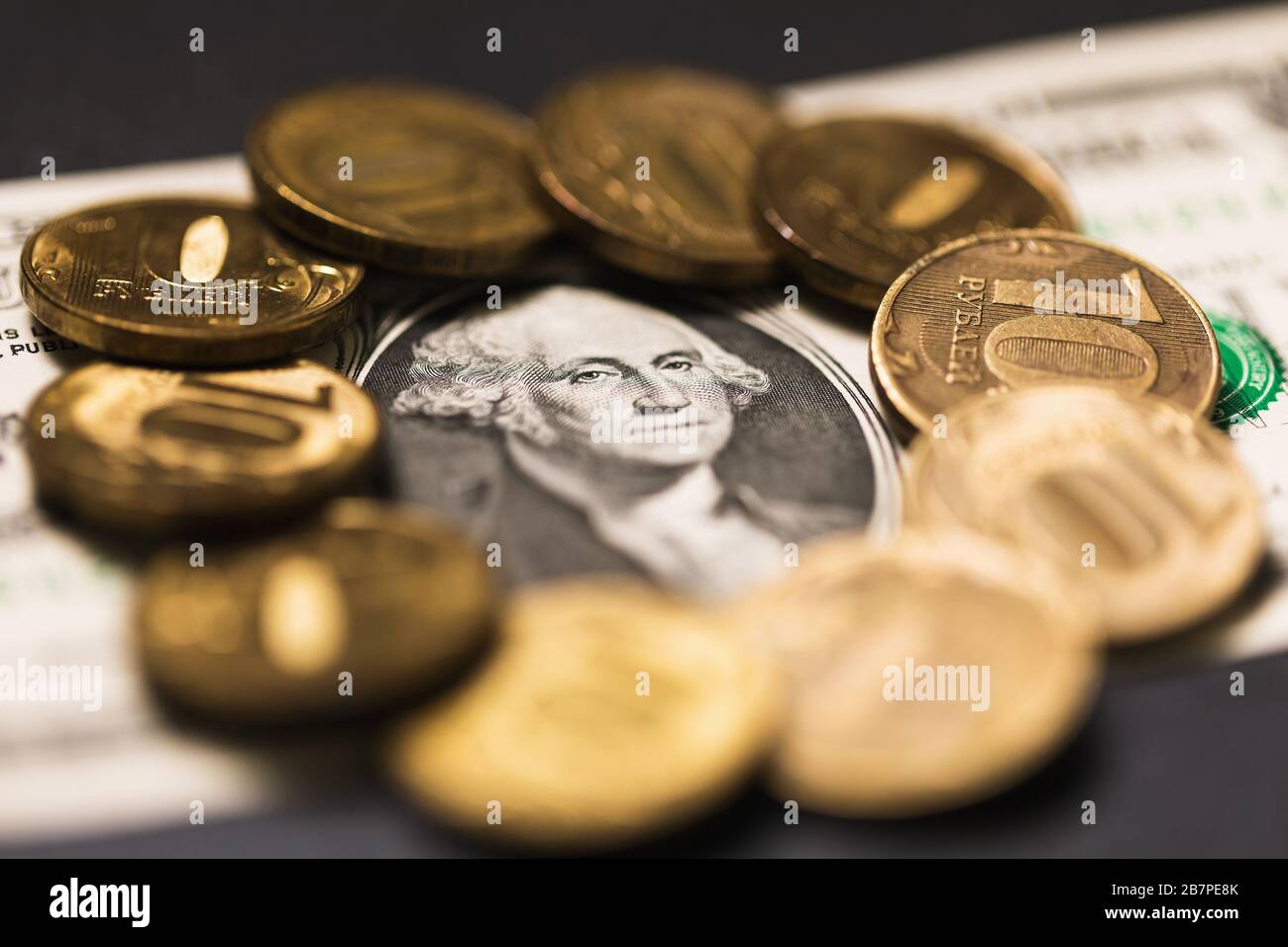 Ein Dollar, umgeben von zehn rubeligen russischen Münzen. Das Konzept für den Anstieg des Dollarpreises auf 100 Rubel Stockfoto