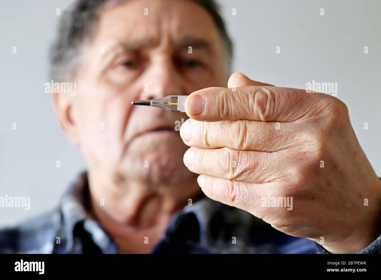 Älterer Mann misst die Körpertemperatur mit einem Quecksilberthermometer. Konzept von Fieber, Kaltbehandlung, Symptome von Coronavirus Stockfoto