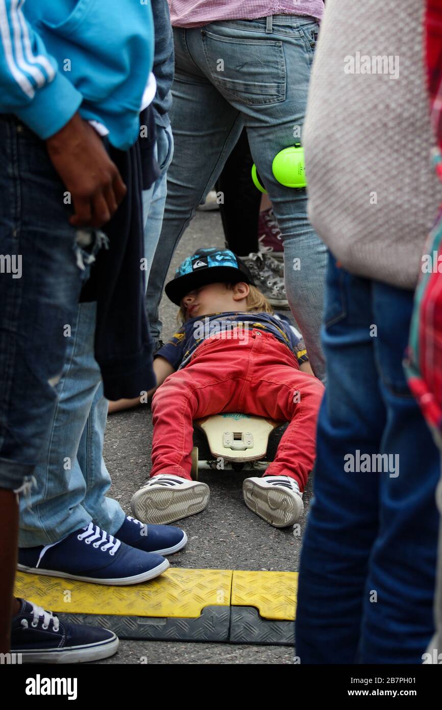 Kleine Kinder schlafen auf einem Skateboard zwischen den Beinen der Mutter während des Freiluftkonzerts Stockfoto