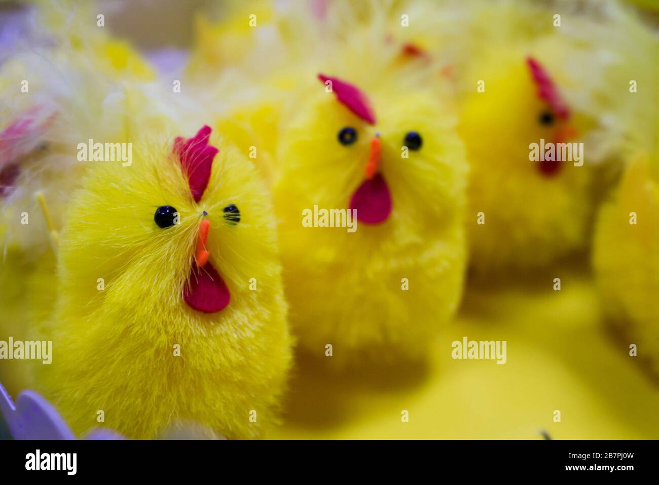 Viele gelbe Kunststoff-Roster in einer Reihe im Supermarkt mit schwarzen Augen und orangefarbenem Schnabel Stockfoto