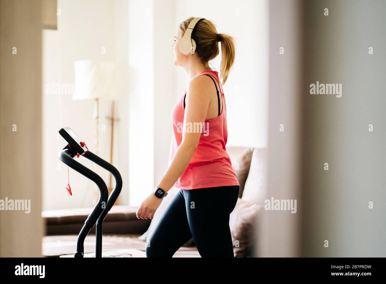 Schöne blonde kaukasische Sportlerin, die Übungen mit elastischem Band im Wohnzimmer zu Hause macht Stockfoto