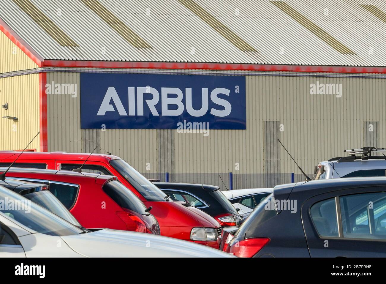 BROUGHTON, WALES - MÄRZ 2020: Schild an der Seite eines Fabrikgebäudes im Airbus-Werk in Broughton, wobei die Autos der Mitarbeiter im Vordergrund stehen. Stockfoto