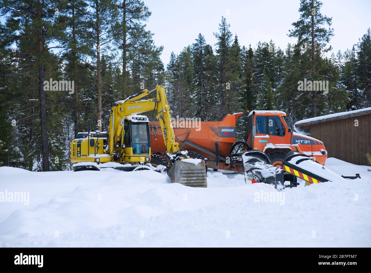 Doosan Moxy MT 31 Dump Truck und Komatsu PW 148 Excavator im Schnee Stockfoto