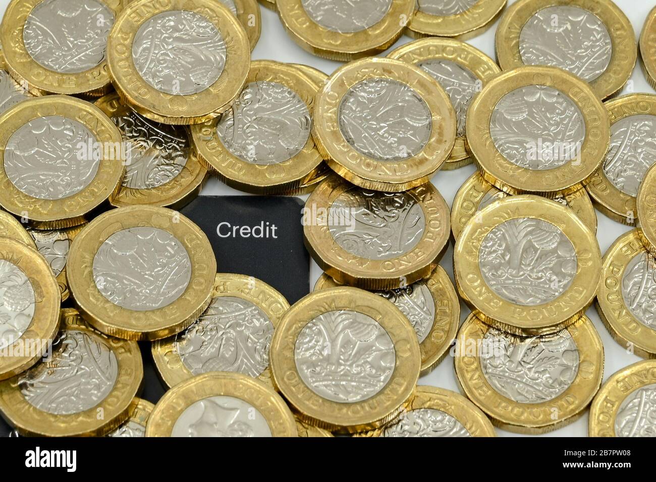 LONDON, Großbritannien - JANUAR 2020: Nahaufnahme der britischen Währung Great British Pound GBP - One Pound Coins um die Ecke einer Kreditkarte Stockfoto