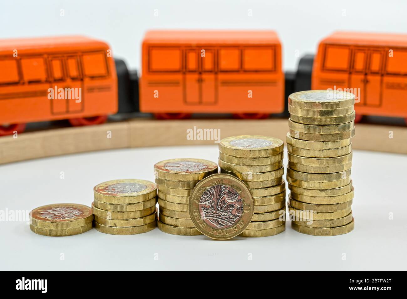 LONDON, Großbritannien - JANUAR 2020: Nahaufnahme von Säulen britischer Ein-Pfund-Münzen in aufsteigender Reihenfolge mit einem Holzspielzeugzug, der im Hintergrund verschwommen ist Stockfoto