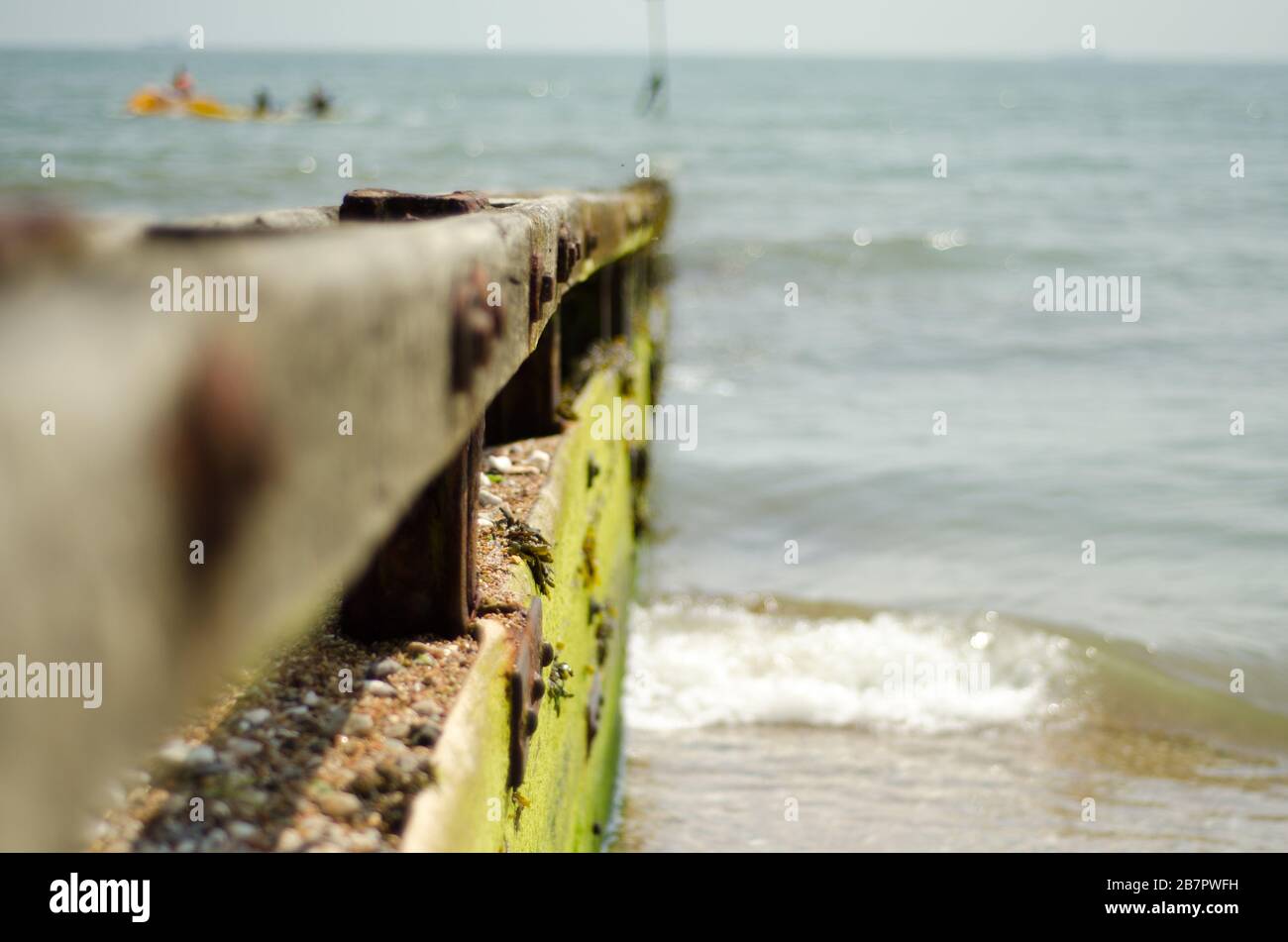 Ein Wetter schlug Holzgroyne auf einer Insel von Wight Shingle Strand, der glatt von Wellen getragen wurde. Stockfoto