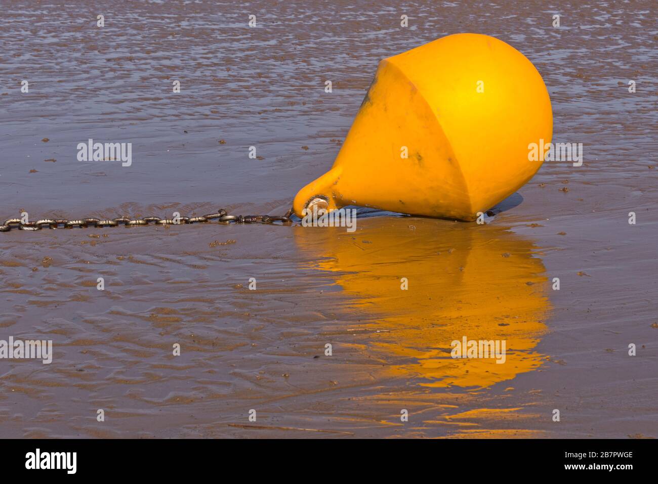 Eine leuchtend gelbe Spezial-Markierboje hoch und trocken auf dem Schlamm neben dem Wrack von SS Norden am Strand bei Berrow an der Küste von Somerset. Stockfoto