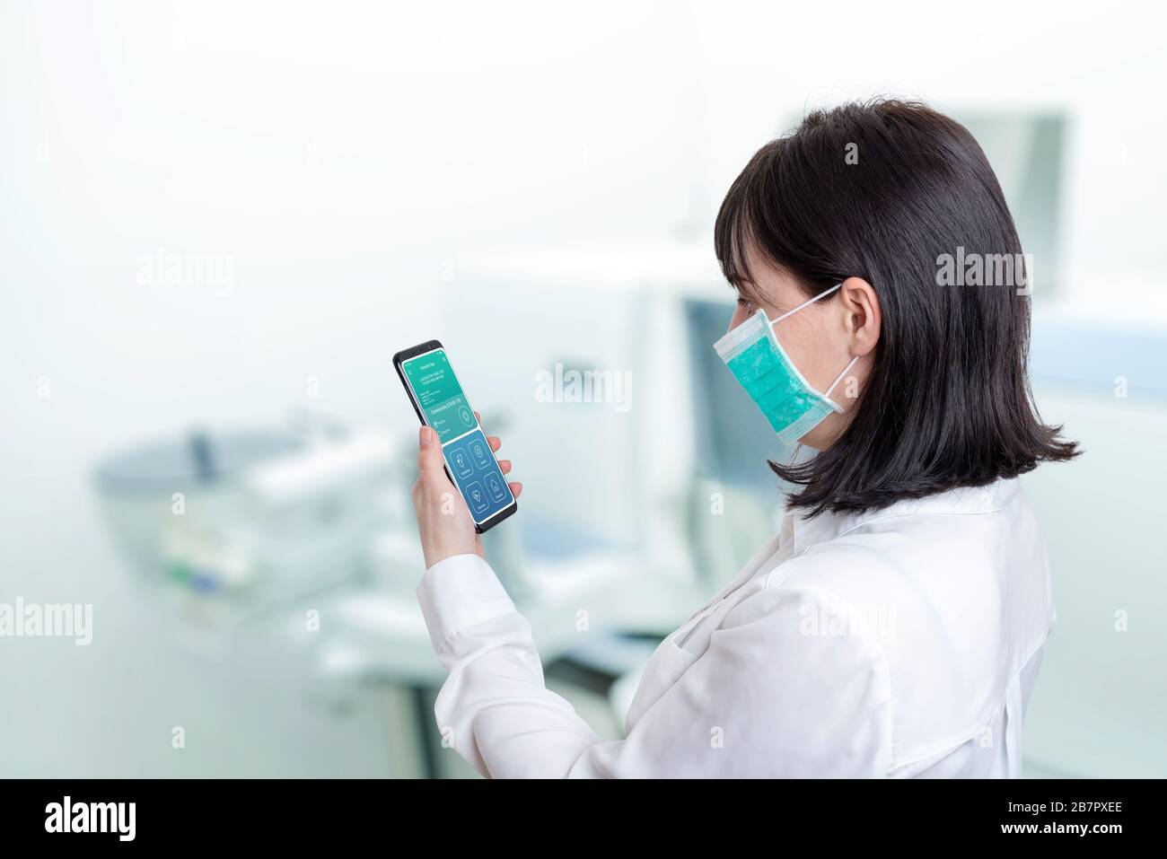 Frau in einem Krankenhauslabor hält ein Telefon mit den Ergebnissen eines Patienten, der positiv für ein Corona-Virus-Konzept ist Stockfoto