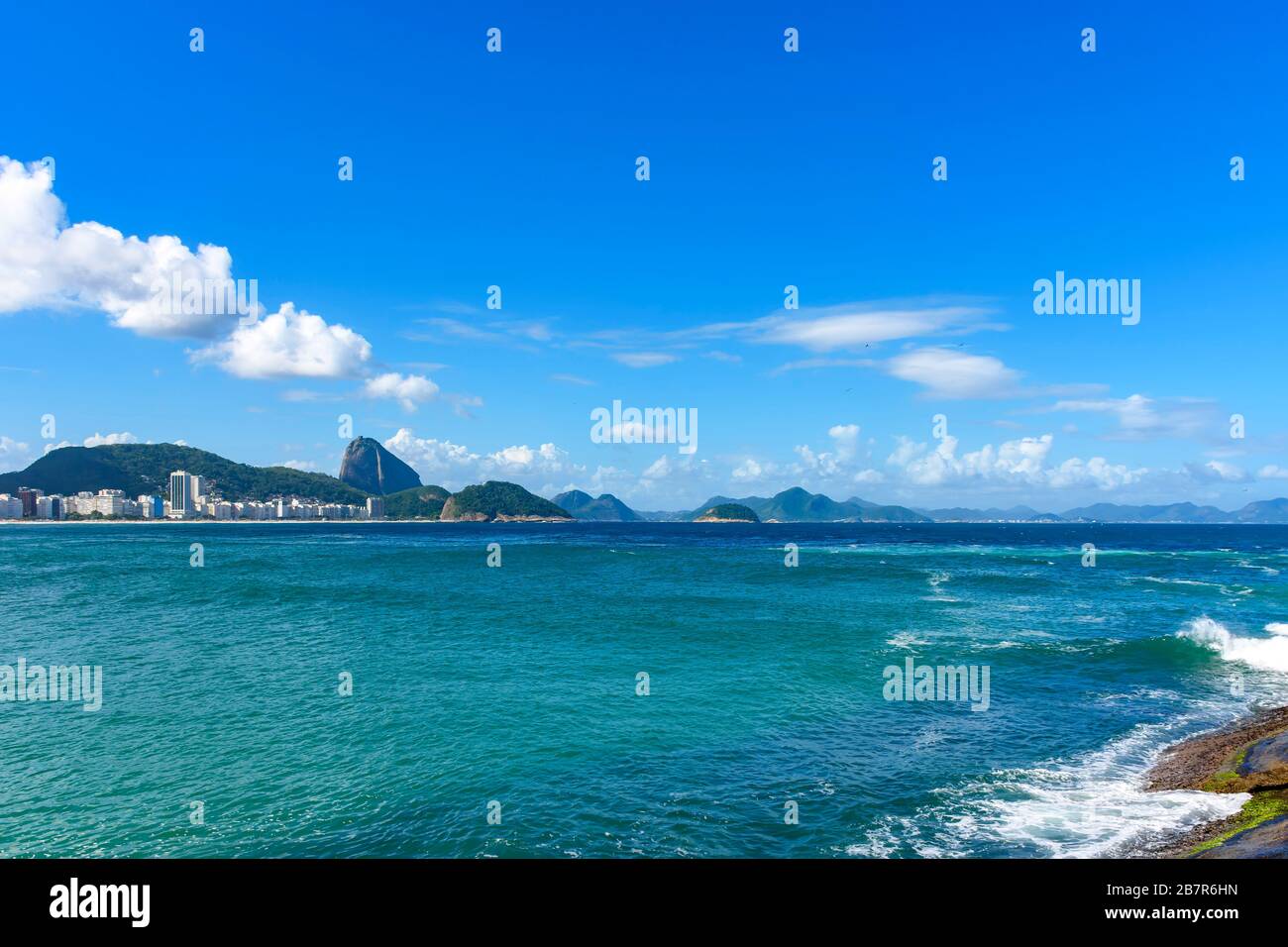 Sonniger Tag am Strand von Copacabana mit den Hügeln von Rio de Janeiro im Hintergrund Stockfoto