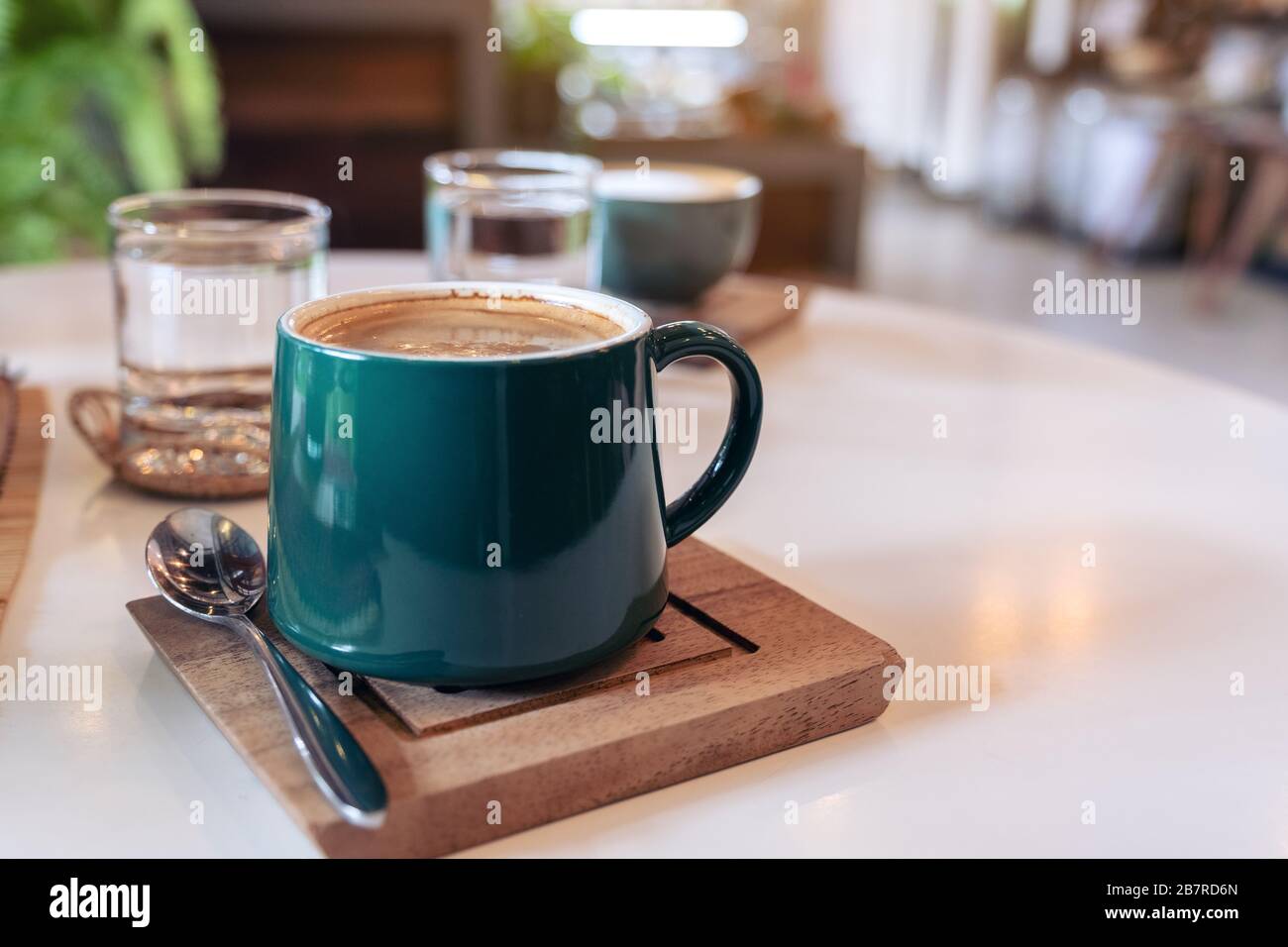 Nahaufnahme von grünen Tassen heißen Kaffees und Gläsern Wasser auf dem Tisch im Café Stockfoto