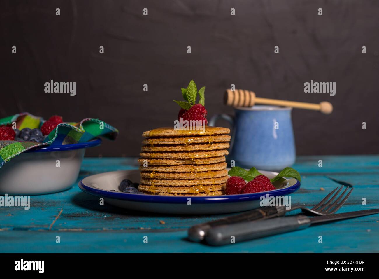 Holländisches Waffelfrühstück mit Himbeere, Blaubeere auf blauem Holzhintergrund. Isoliertes Bild. Vorderes Bild. Frühstückskonzept. Stockfoto