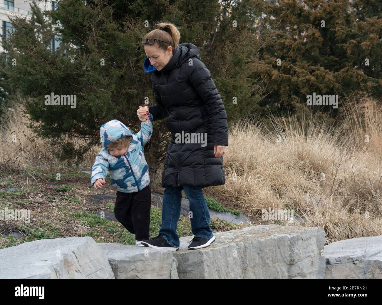 Eine Mutter half ihrer Tochter dabei, sich über einige große Steine im Hudson River Park zu klauen. Der Park verläuft entlang des Hudson River zwischen Chambers Street und MID Stockfoto