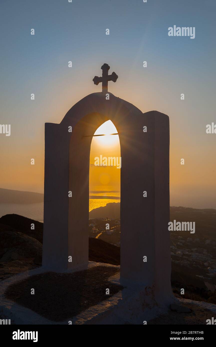 Sonnenuntergang in und hinter der Silhouette White Bogen of Church mit Kreuz auf Santorini Griechenland während Sonnenuntergang in der Dämmerung Stockfoto