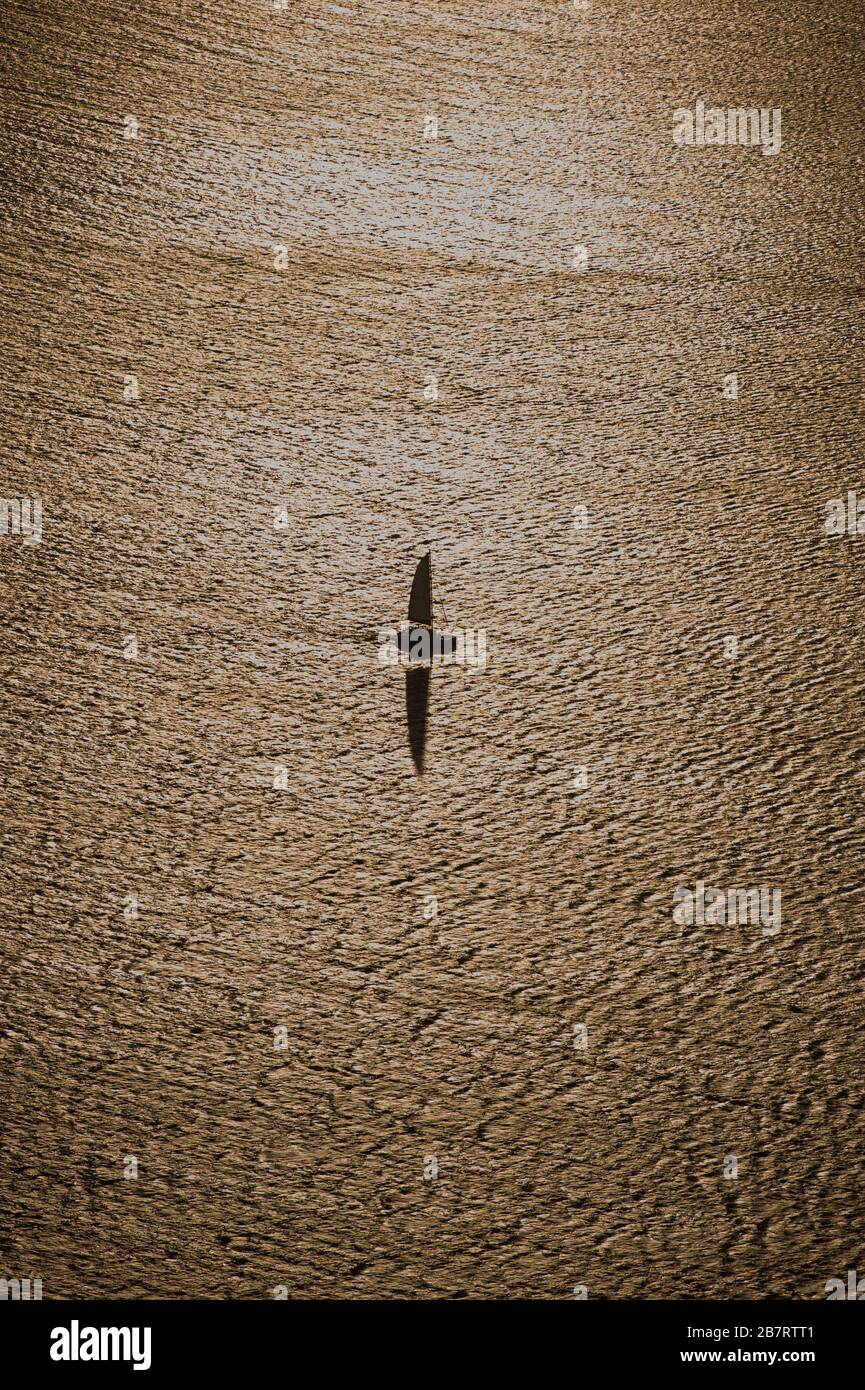Ein einzelnes Segelboot segeln in Full Sail im Goldenen Meer bei Dusk in Griechenland Darstellung Ruhe und Frieden in offenen Gewässern Stockfoto