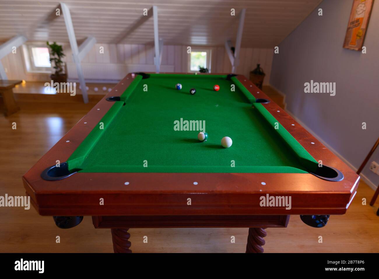 Holz-Billiard-Tisch mit Kugeln, die oben in einem gemütlichen Loft-Zimmer verstreut sind Stockfoto