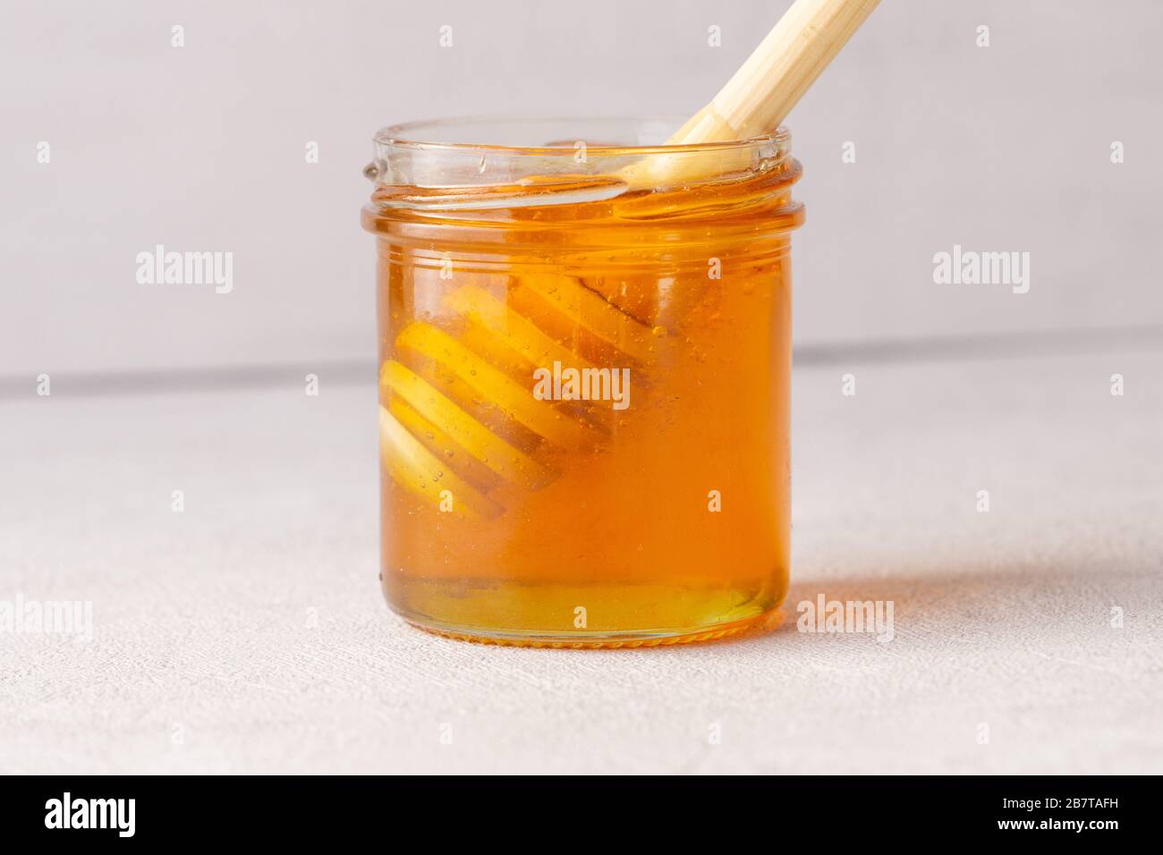 Honigbecher, Topf, Holzlöffel im Inneren. Nahaufnahme: Gesundheitswesen, Medizin. Stockfoto