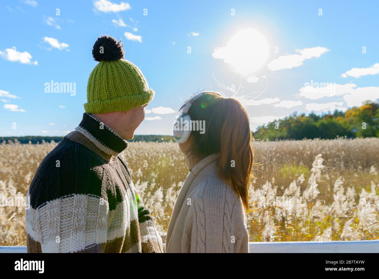 Fröhliches junges, multiethnisches Paar, das zusammen einen malerischen Blick auf das Herbst-Bulrush-Feld hat Stockfoto