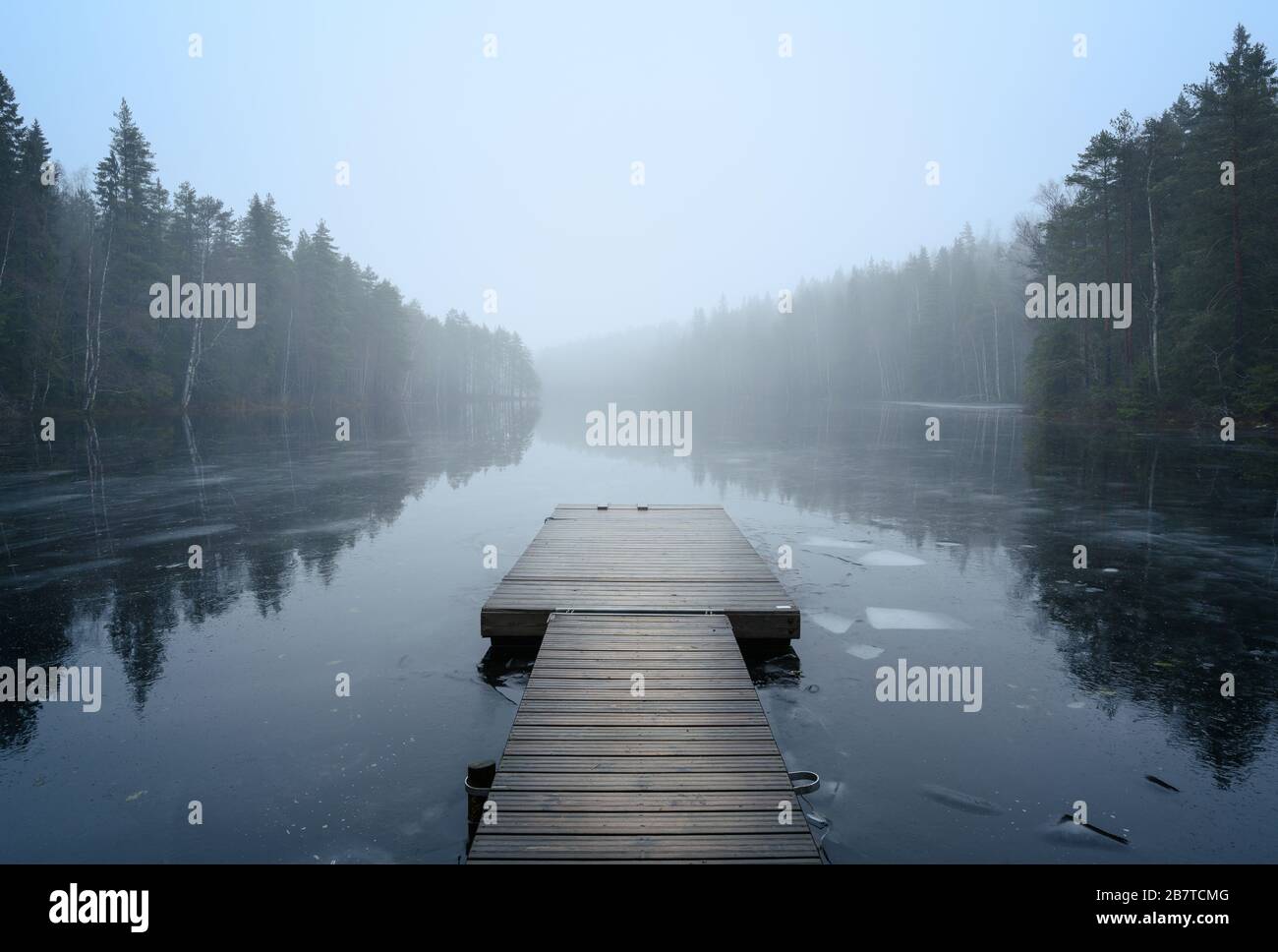 Nebelige Landschaft mit ruhigem See und Pier. Nebel über Wasser. Nebelige Luft. Frühkindlicher Morgen im Herbst. Schöner Freiheitsmoment und friedliche Atmosphäre Stockfoto