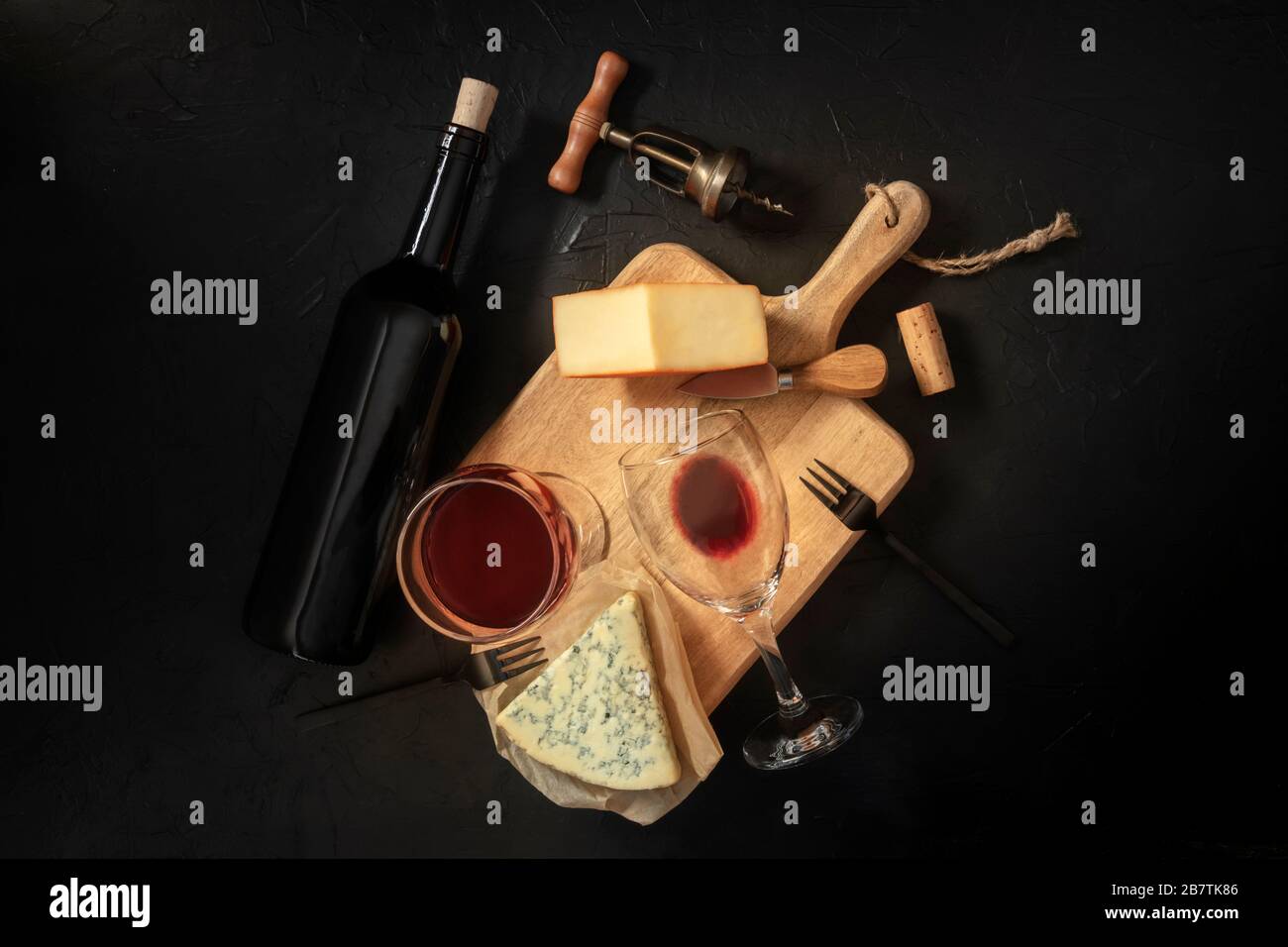 Wein- und Käseverkostung, oben auf schwarzem Hintergrund mit Kork, Korkenzieher und einer Flasche Stockfoto