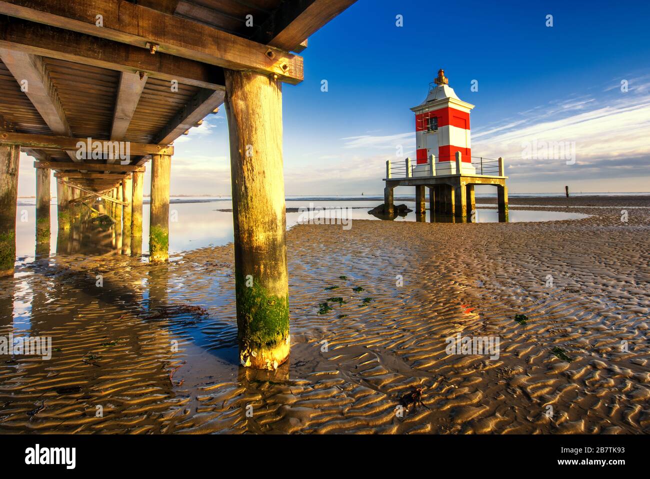 Pier und Leuchtturm bei Sonnenuntergang und Ebbe. Lignano Sabbiadoro, Provinz Udine, Friuli Julisch Venetien, Italien. Adriatische Meereslandschaft. Stockfoto