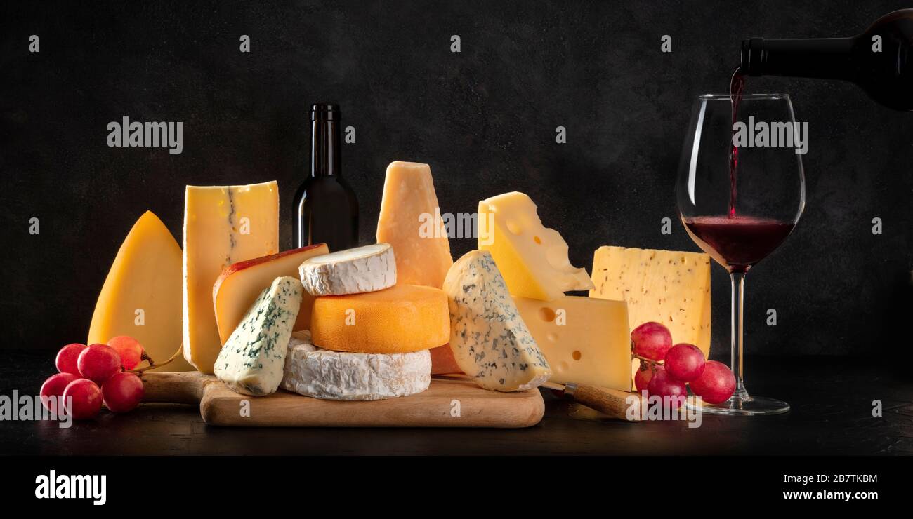 Käsepanorama, viele verschiedene Arten von Chees mit Trauben und Gießwein, eine Seitenansicht auf dunklem Hintergrund mit Kopierraum Stockfoto