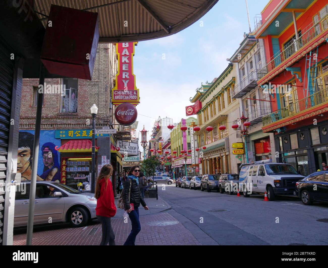 San Francisco, Kalifornien - Juli 2018: Reihen farbenfroher Gebäude mit zwei Frauen, die darauf warten, die Straße in Chinatown, San Francisco, zu überqueren. Stockfoto