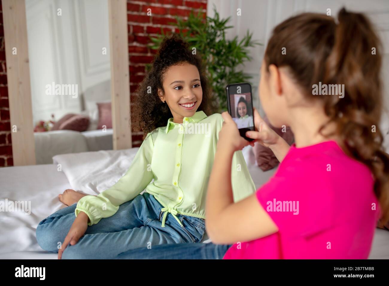 Mädchen in einem bestechenden Tshirt, das einen selfie ihres Freundes macht Stockfoto