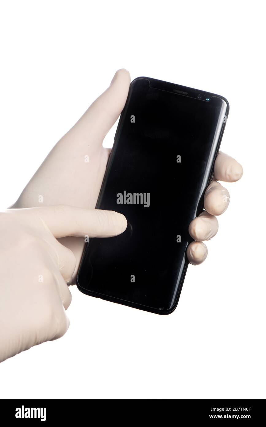 Mit einem Handy mit weißen Schutzhandschuhen Stockfoto