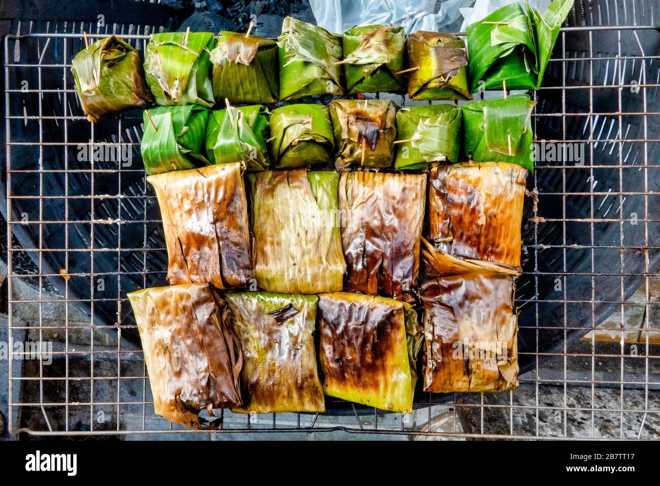 Khao tom, traditionelles thailändisches und laotisches Dessert, das aus gewürztem, gedämpftem, klebrigem Reis besteht, der in Bananenblätter eingewickelt ist Stockfoto