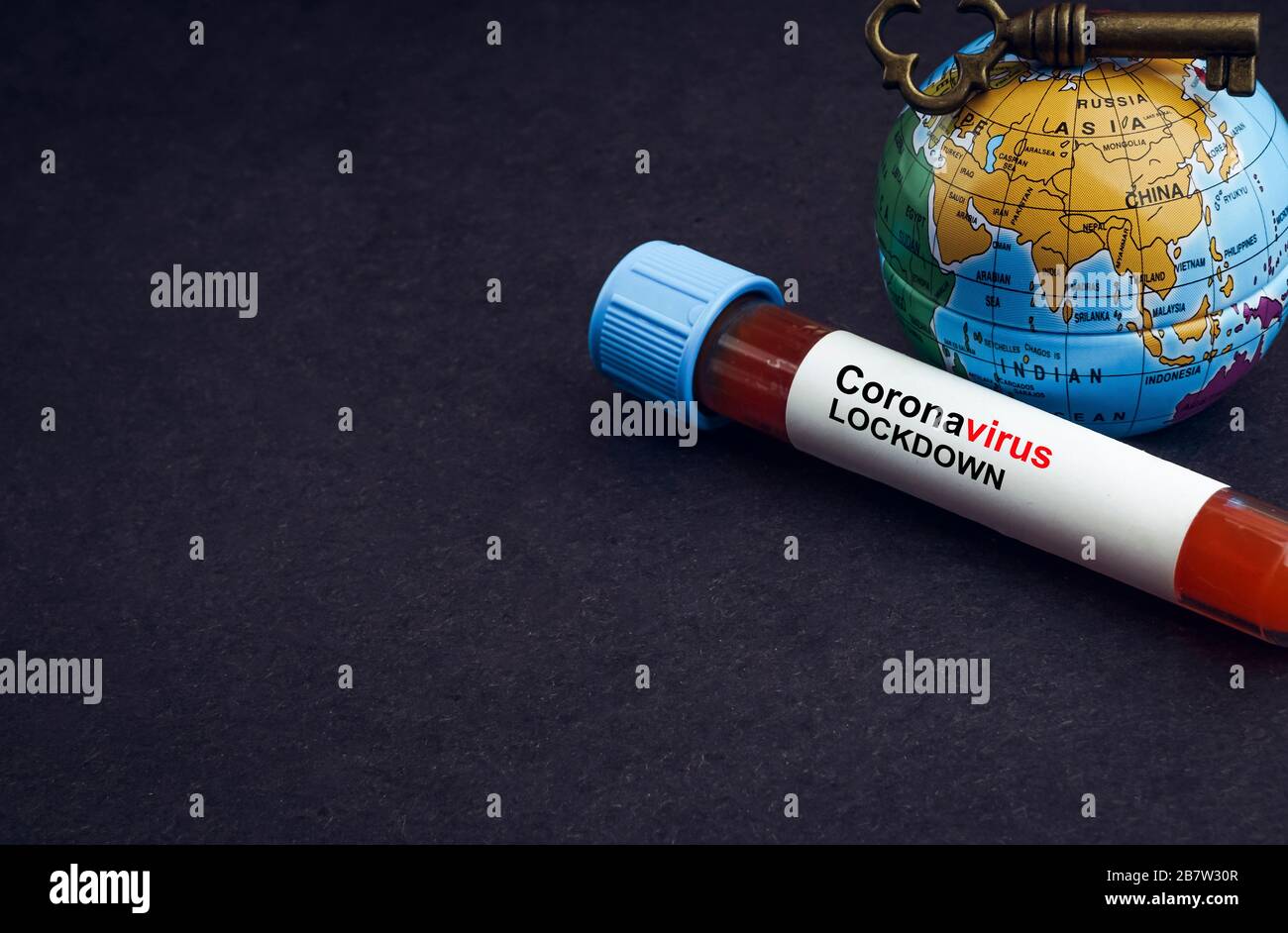 CORONAVIRUS LOCKDOWN-TEXT mit Weltkugel, Schlüssel und Bluttestvakuumschlauch auf schwarzem Hintergrund. Covid-19 oder Coronavirus Konzept Stockfoto