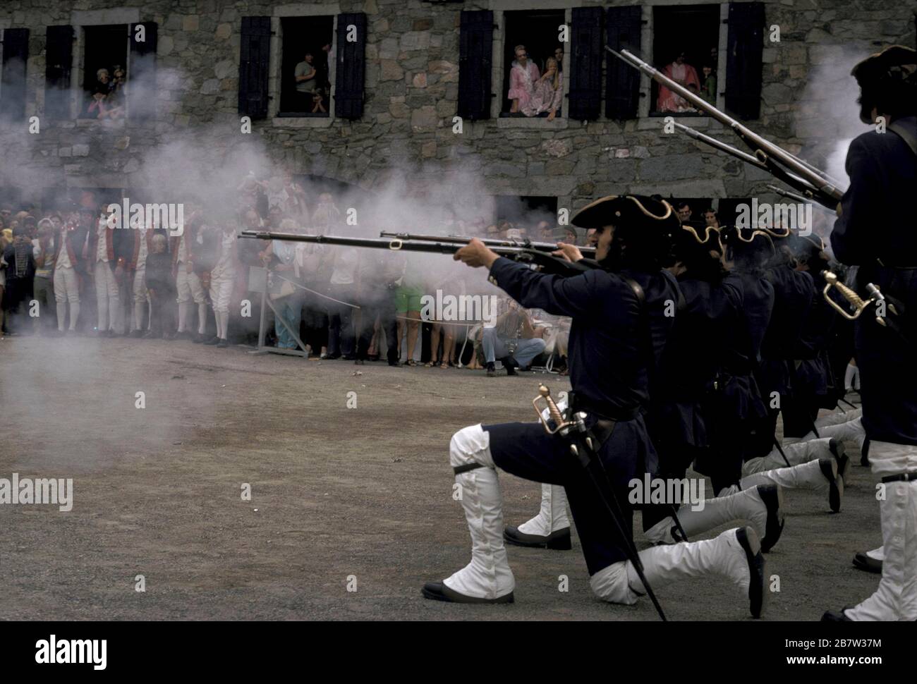 Fort Ticonderoga, New York: Besucher des historischen Forts sehen sich die Demonstration historischer Reenaktoren an, die als Soldaten verkleidet sind, die Gewehre abfeuerten. ©Bob Daemmrich Stockfoto Fort Ticonderoga, New York: Besucher des historischen Forts sehen sich die Demonstration historischer Reenaktoren an, die als Soldaten verkleidet sind, die Gewehre abfeuerten. ©Bob Daemmrich Stockfoto