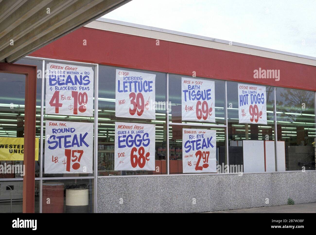 Lebensmittelpreisschilder im Fenster eines kleinen Supermarkts. ©Bob Daemmrich Stockfoto