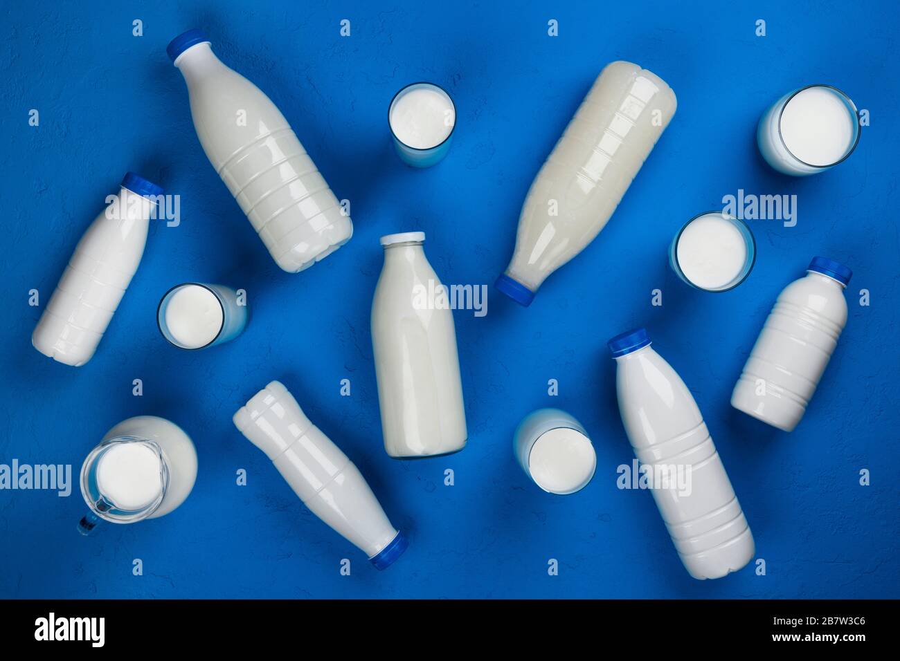 Milchprodukte, Flaschen und Gläser mit Milch auf blauem Hintergrund, Draufsicht Stockfoto