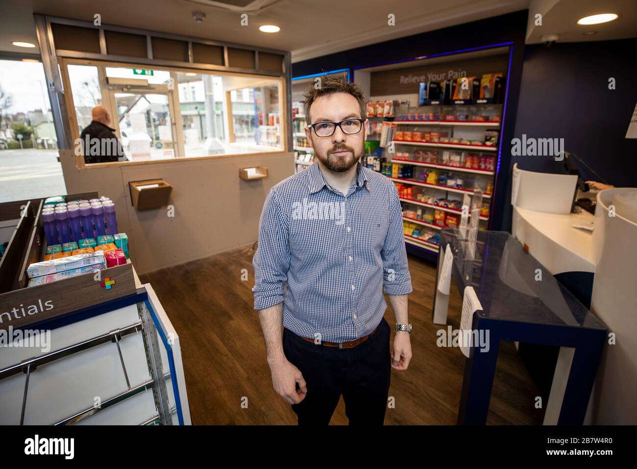 Peter Rice, Group Manager der McKenzie's Pharmacy an der Falls Road in Belfast neben ihrem neu installierten Ladentisch. Der Schalter im Poststil wurde so konstruiert, dass Mitarbeiter und Kunden vor Coronavirus geschützt werden. Stockfoto