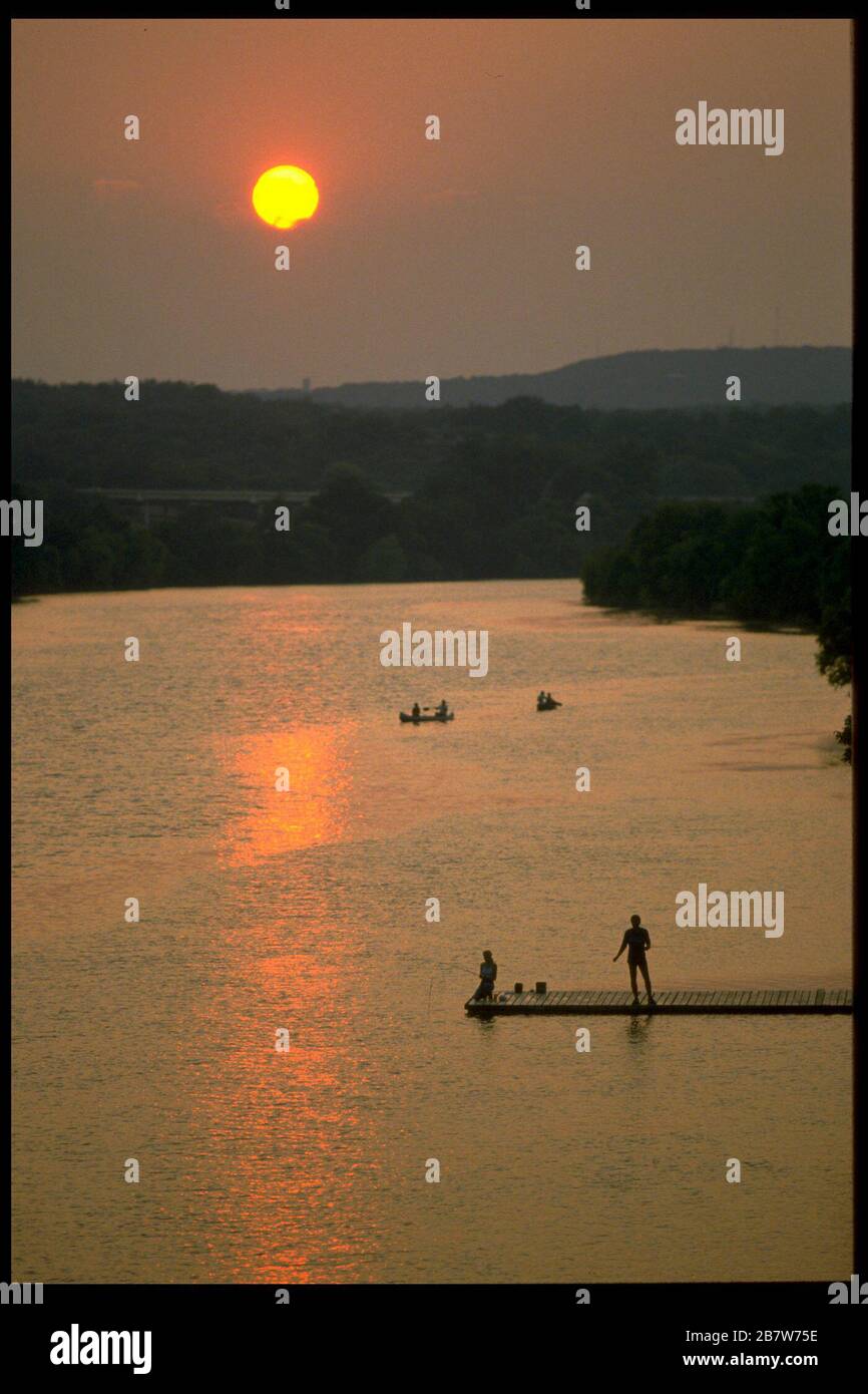 Austin Texas USA: Bootsfahrer und Menschen, die am Pier angeln, genießen den Sonnenuntergang über dem See. Austin. ©Bob Daemmrich Stockfoto