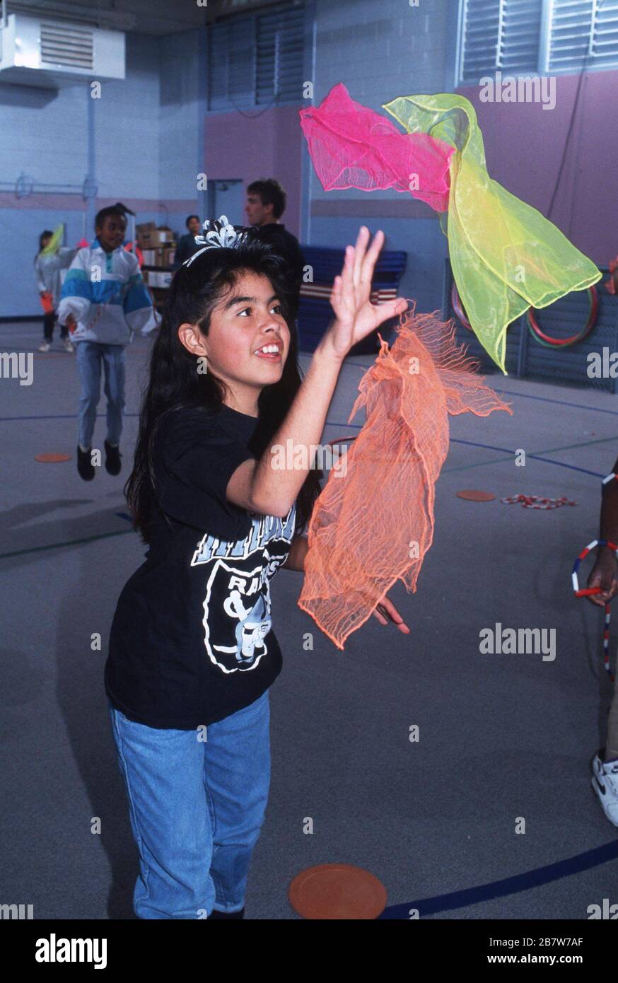 Austin Texas USA: Mädchen der fünften Klasse fängt Schals, die von einem Partner während der Sportausbildung in der Schulhalle geworfen werden. ©Bob Daemmrich Stockfoto