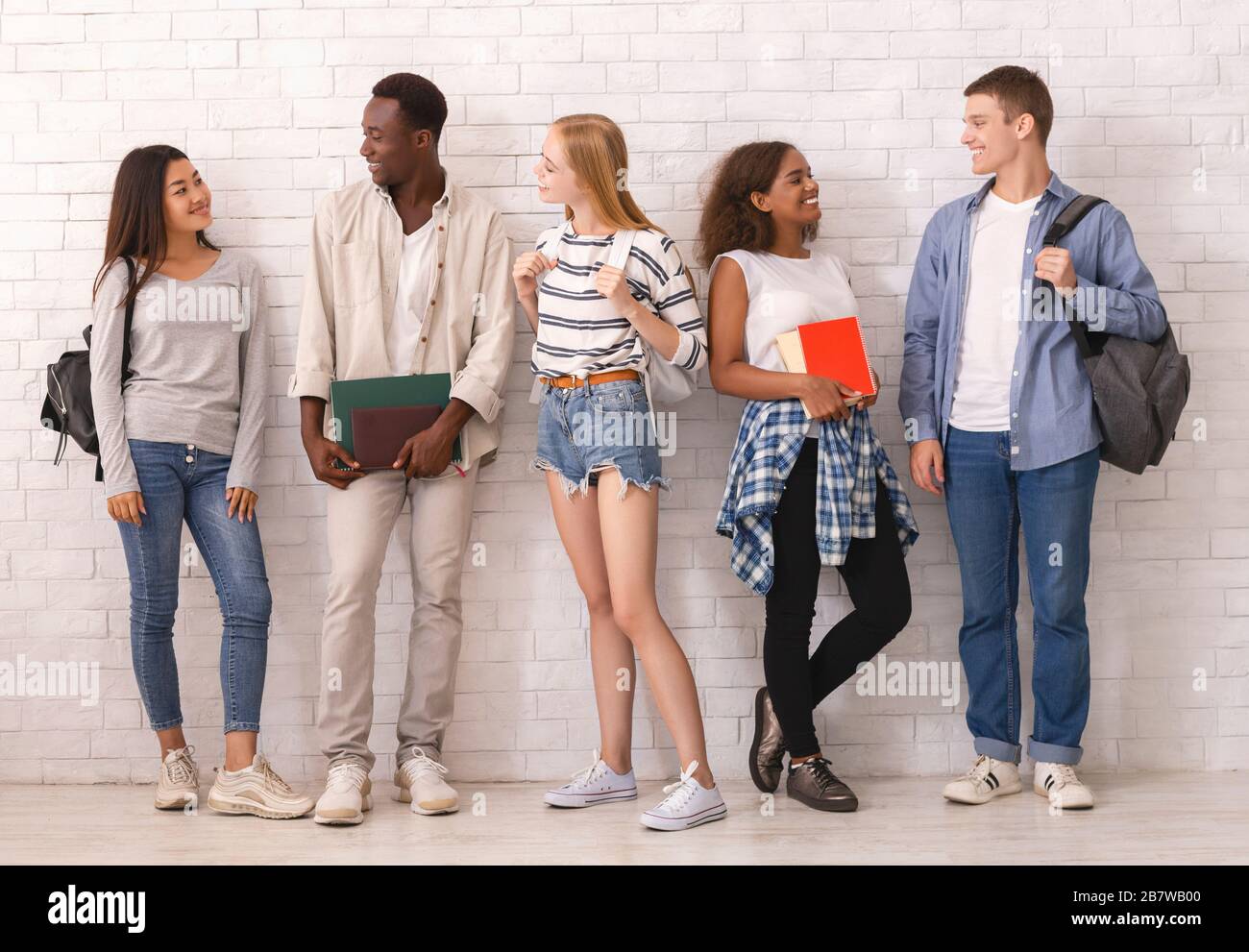 Sorglose Gruppe multiethnischer Studenten, die vor der Universität ein Gespräch führen Stockfoto