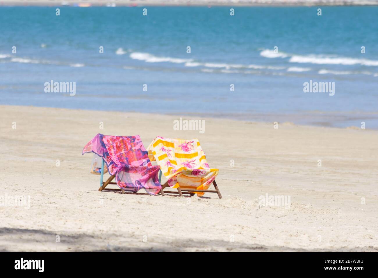 Buntes Material bedeckt das Bett am Meer im Strandhintergrund. Stockfoto