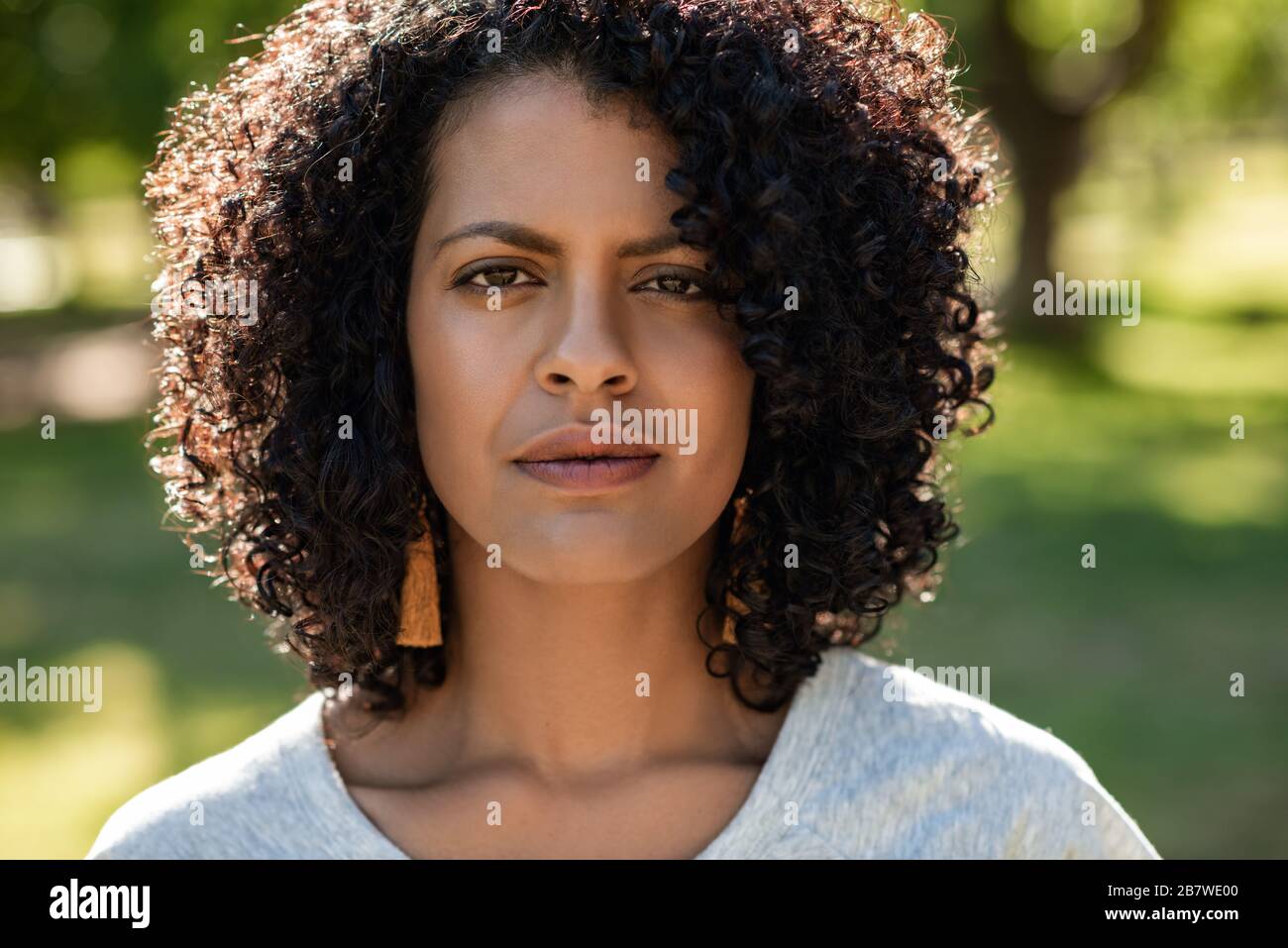 Selbstbewusste junge Frau, die im Sommer in einem Park steht Stockfoto