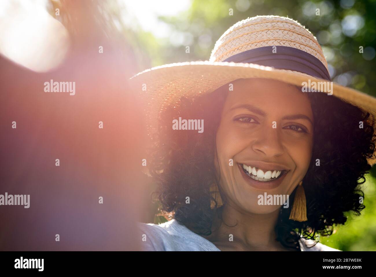 Lächelnde Frau, die einen Sonnenhut trägt und Selfies spricht Stockfoto