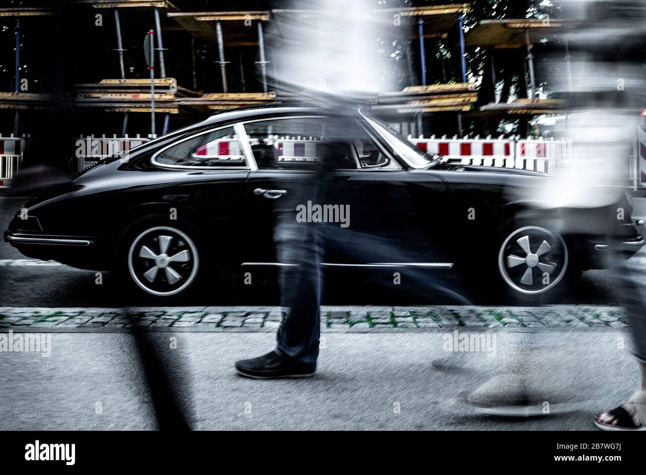 Die klassische Schönheit des Parkens, der 911-Porsche-Jahrgang, als Menschen, die in monochromatischem Stil vorbeiziehen, auf dem Foto der Stadt München Stockfoto