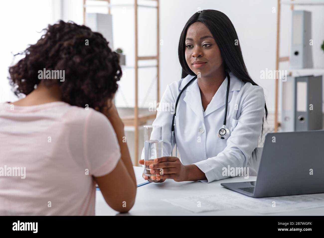 Die schwarze Ärztin tröstet ihre weinende Patientin Stockfoto