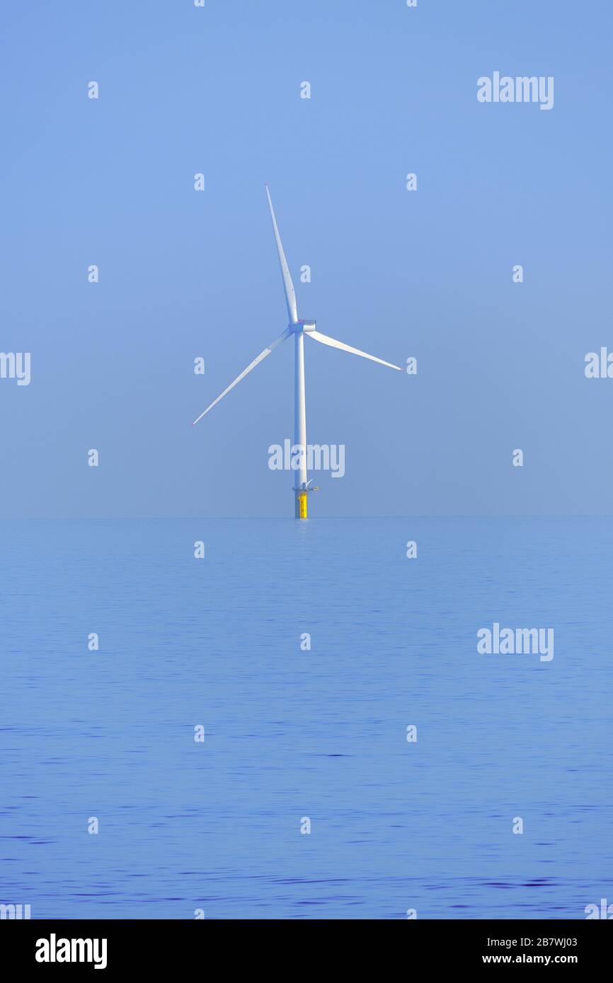 Umgang mit dem Klimawandel durch die Politik der erneuerbaren Energien mit Technologien wie dieser Küstenwindturbine im Meer. Stockfoto