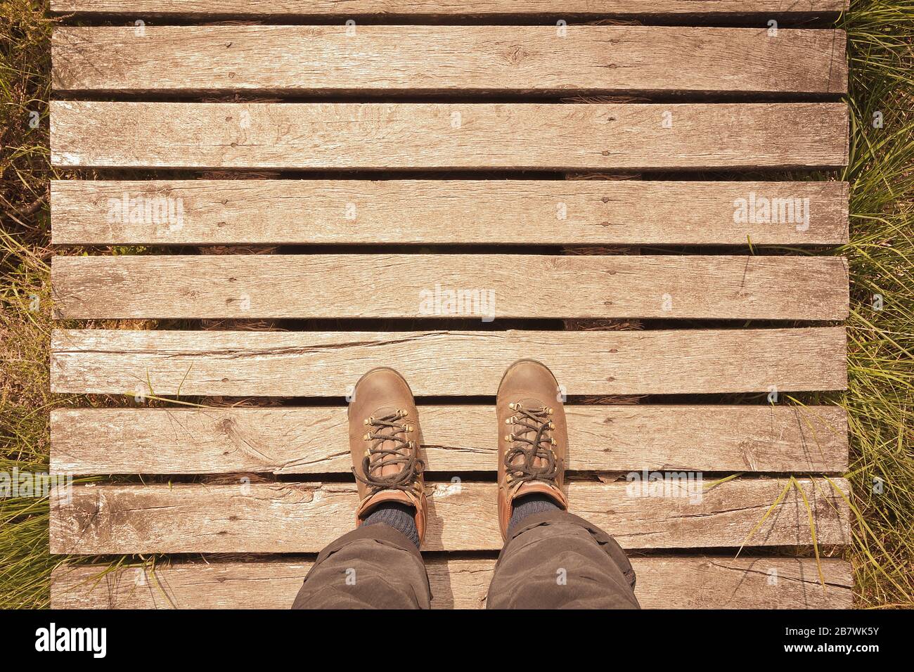 Wanderschuhe auf einem Holzsteg mit Kopierraum, Pov-Konzept, Vintage-Filtereffekt. Stockfoto