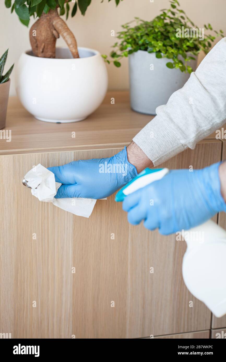 Mann Hände in Handschuhen desinfizieren Kommode Griff, Virus auf Oberfläche töten Stockfoto