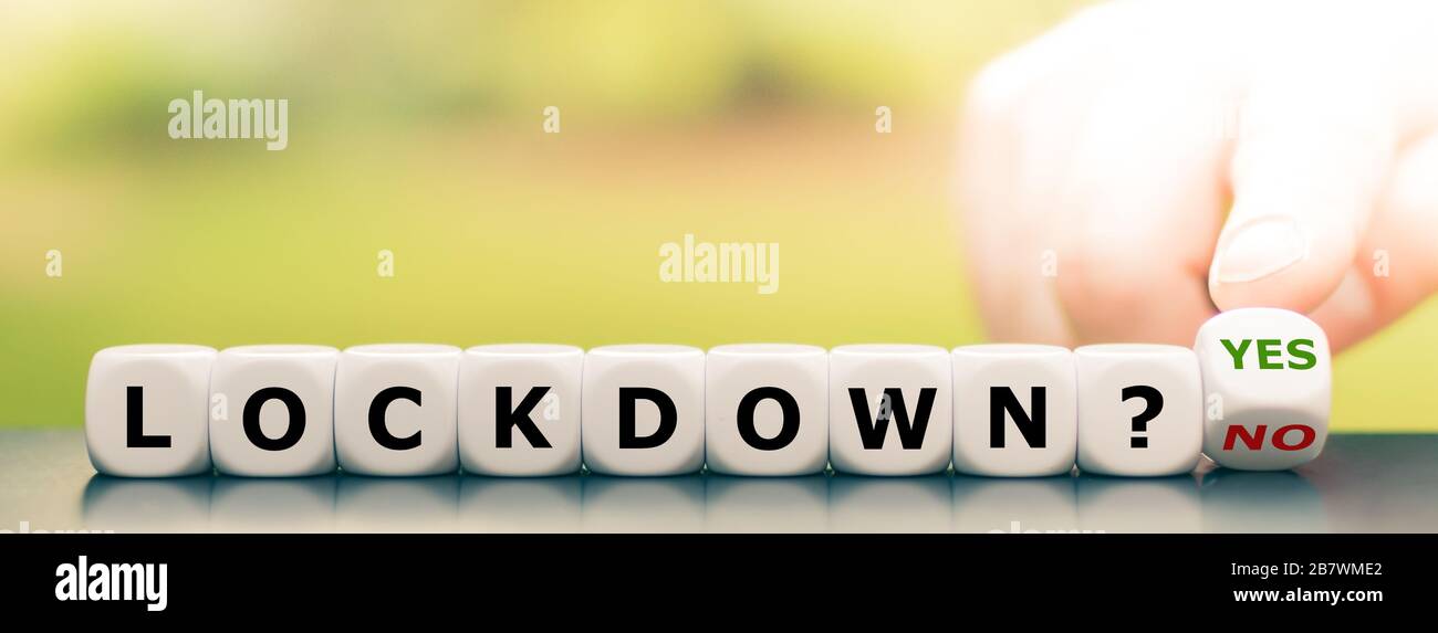 Eine Sperre wegen der Koronakrise? Hand dreht Würfel und ändert den Ausdruck "Lockdown? Nein", um "abzusperren? ja". Stockfoto