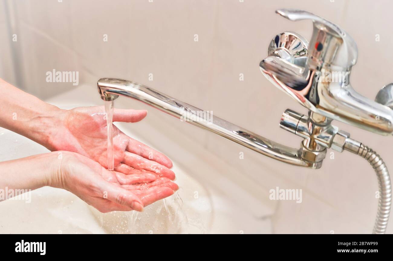 Eine Frau wäscht ihre Hände mit Seife und Wasser aus einem Wasserhahn. Hygiene- und Vorbeugungskonzept. Ein Wasserstrom aus einem Wasserhahn. Stockfoto
