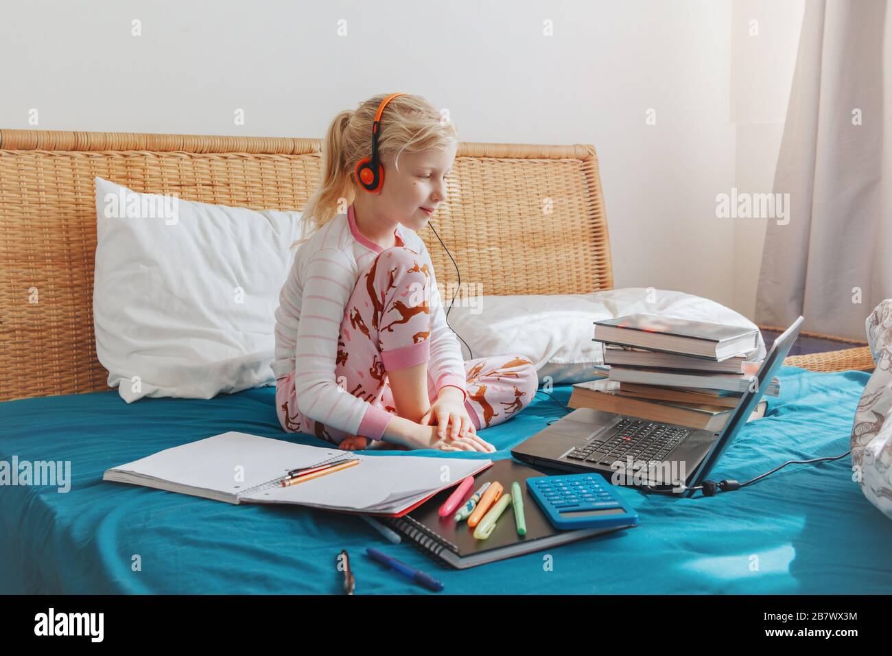 Kaukasisches Mädchen, das im Bett sitzt und online im Laptop lernt. Virtuelle Unterrichtsstunde zum Video während der Selbstisolierung zu Hause. Entferntes Remot Stockfoto