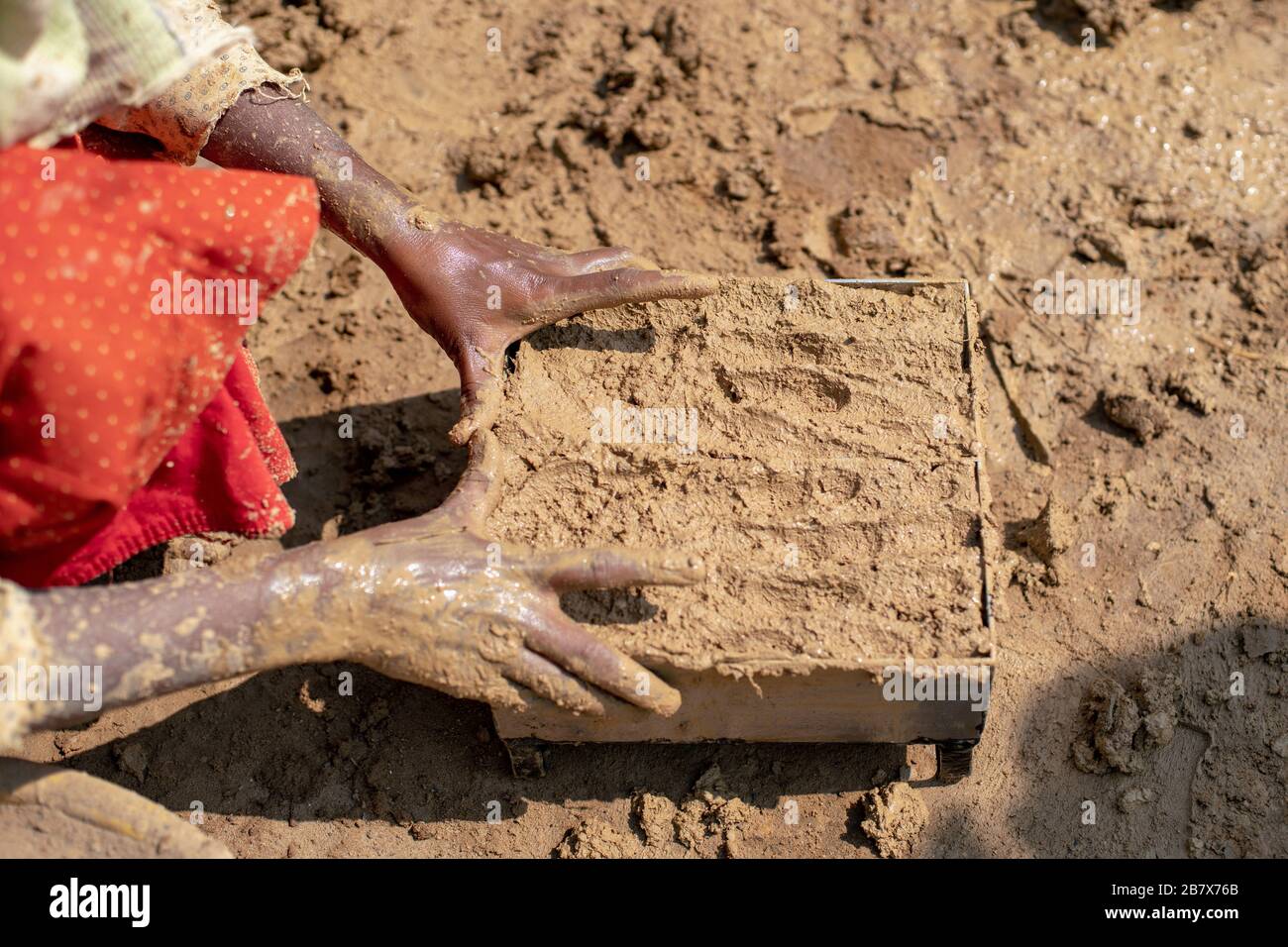 Eine Frau, die Ziegelsteine anstellt, füllt Formen von Hand Stockfoto