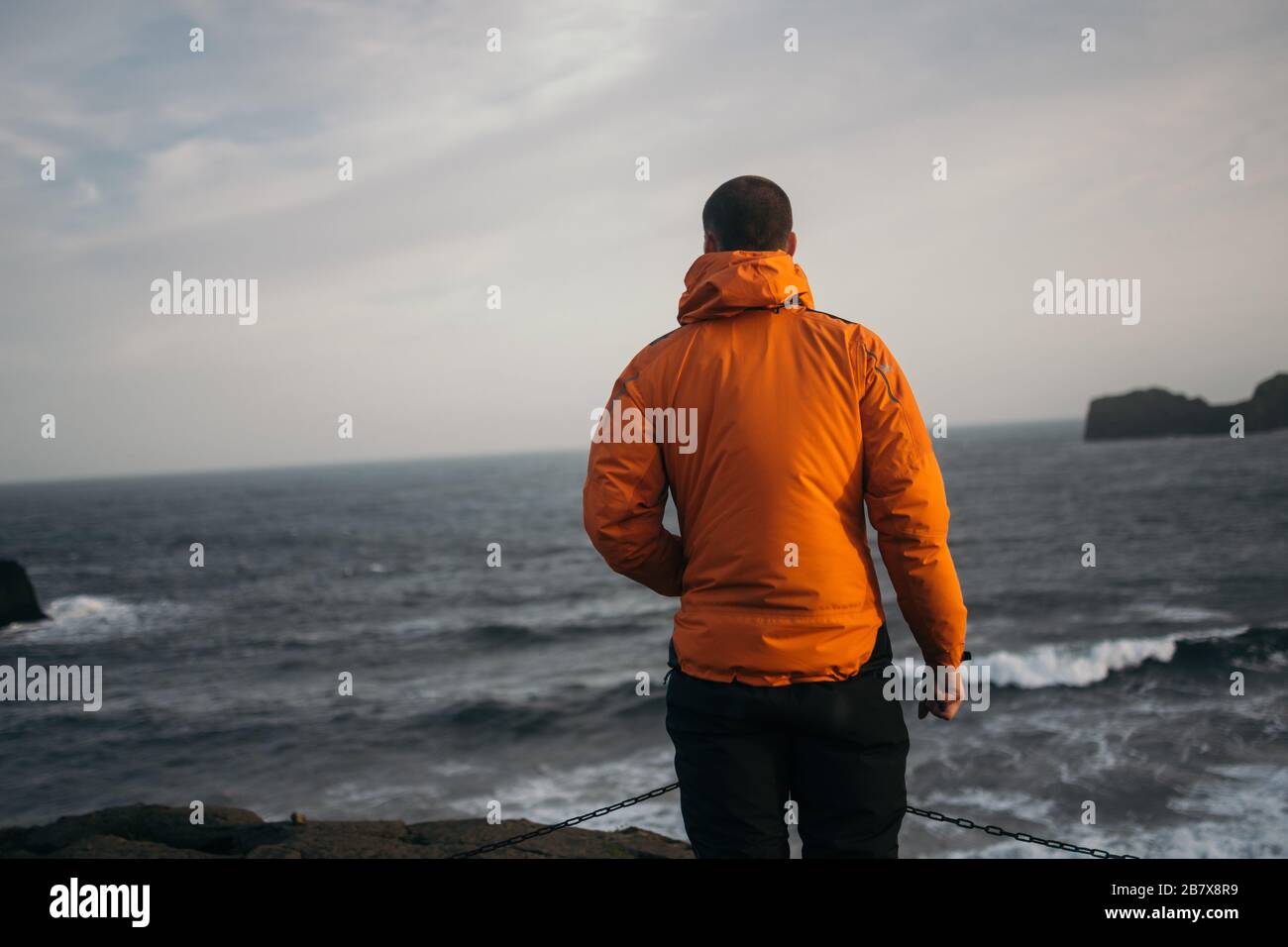 Youngman steht am windigen Strand von DyrhÃ³laey, Island Stockfoto